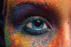 Crop of female eye with colorful make up. Beautiful fashion model with creative art makeup. Abstract colourful splash make-up. Holi festival